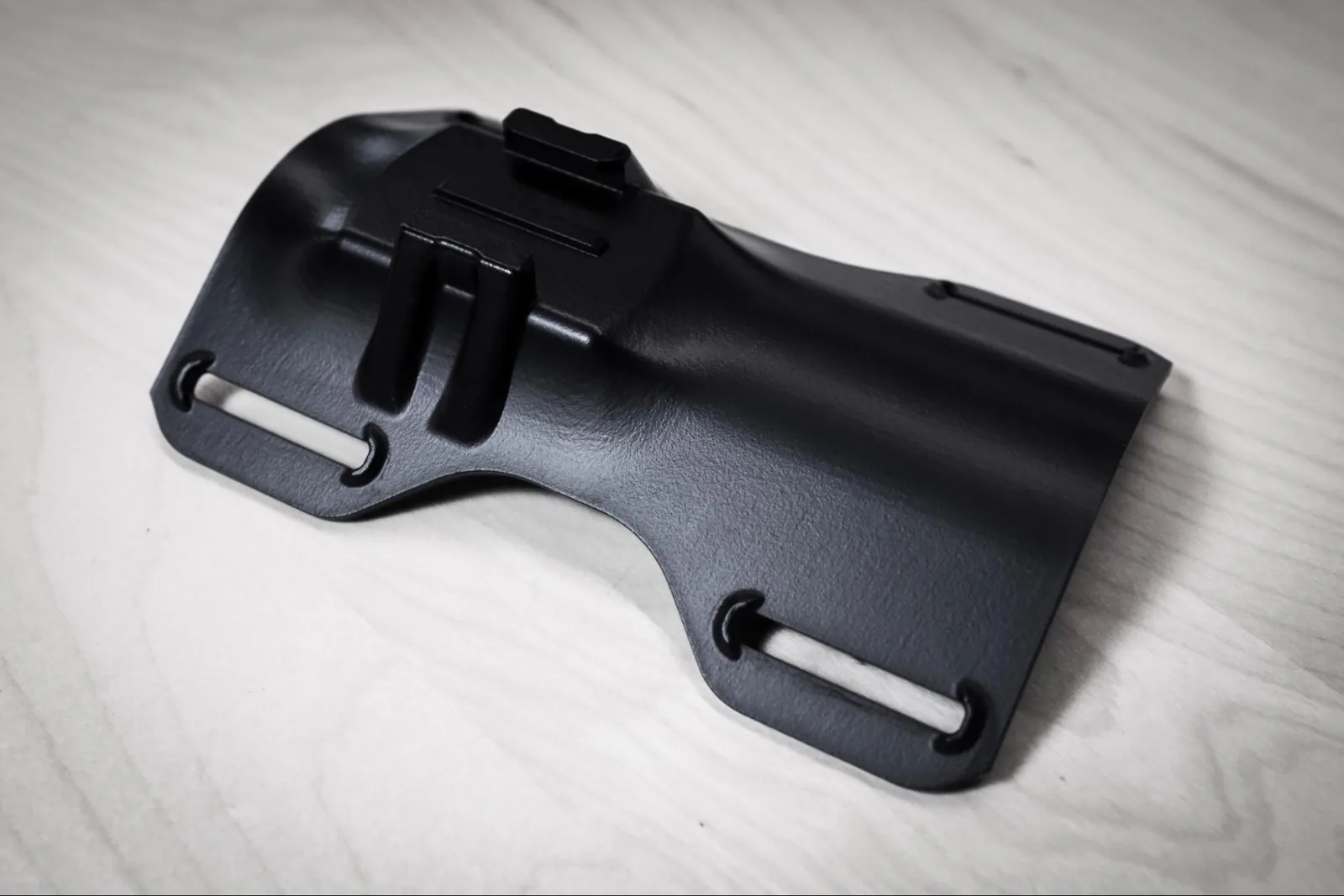 An MJF nylon bracket, printed and finished in black — the kind of end-use part the platform was built around