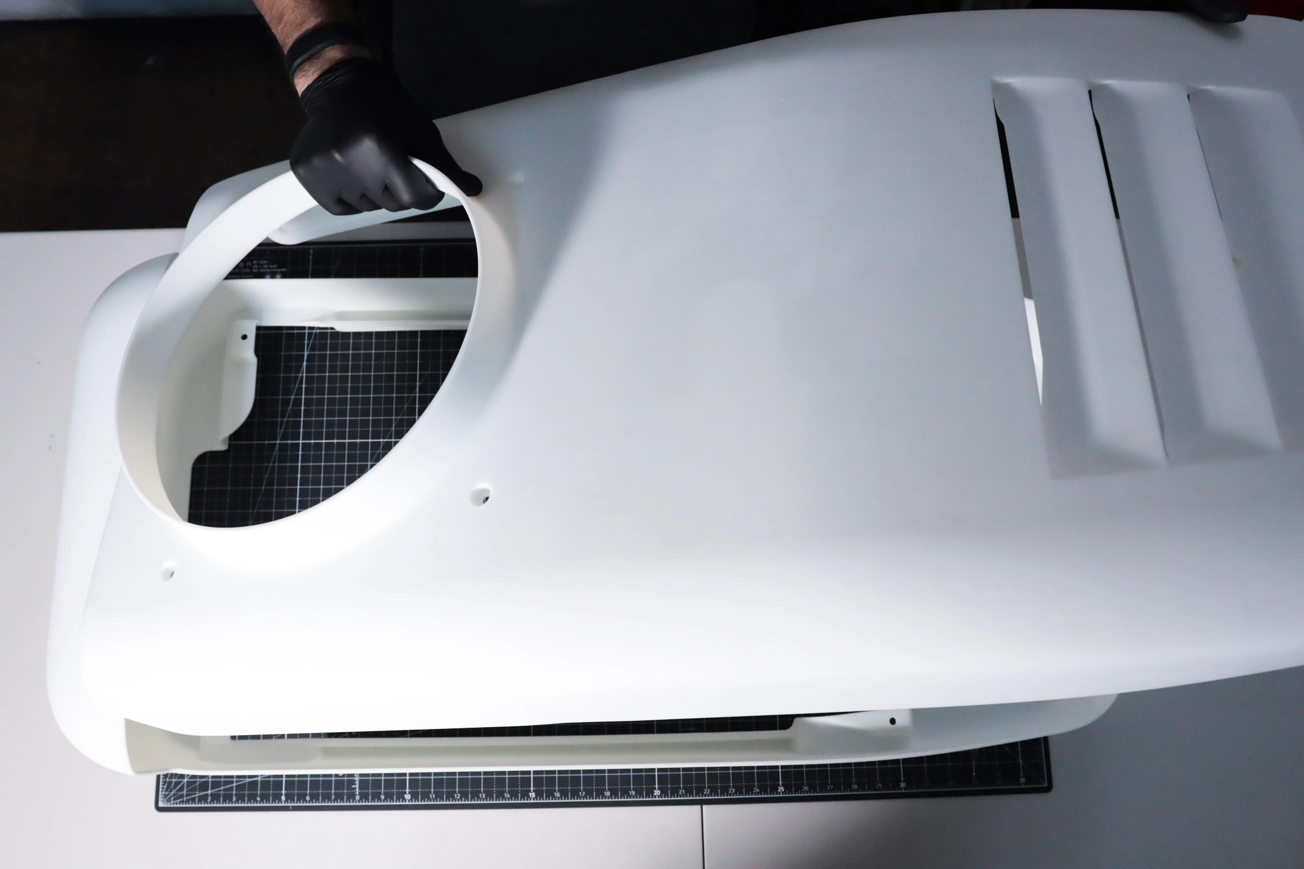 A large industrial SLA housing with smooth surfaces and crisp feature edges, checked on a cutting mat